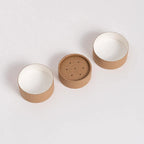 An image of a singular paper shaker tube, displayed in three separate parts, showcasing the top, perforated lid, main body, and the interior against a white background.