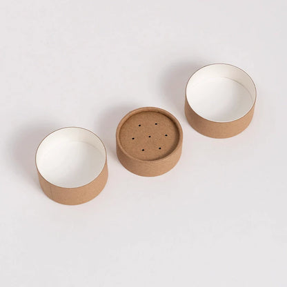 An image of a singular paper shaker tube, displayed in three separate parts, showcasing the top, perforated lid, main body, and the interior against a white background.