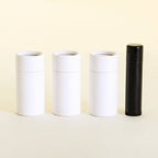  Three closed white cylindrical containers and one black cylindrical container aligned side by side on a pale yellow background.